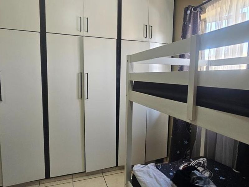 A bedroom featuring floor-to-ceiling built-in cupboards and tiled flooring, providing ample storage space.