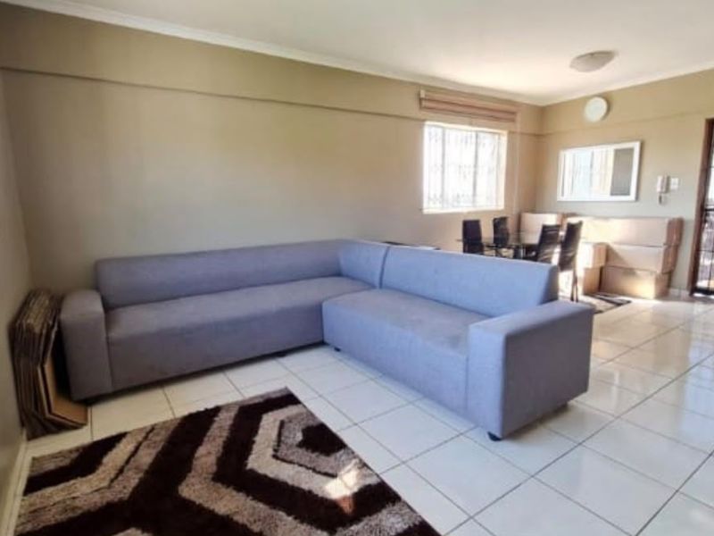 Open plan living and dining area featuring tiled flooring, security bars on windows, and a secure entrance door.