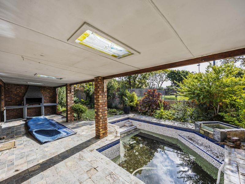Covered patio area featuring a built-in brick braai and an adjacent swimming pool, offering potential for outdoor entertainment renovation.