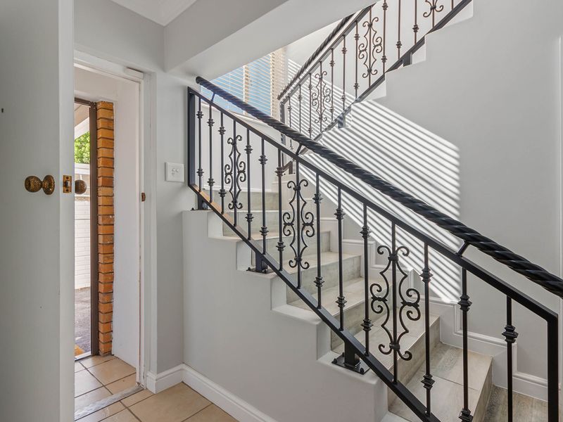 An entrance area featuring a tiled staircase with a decorative wrought iron balustrade and neutral wall finishes.
