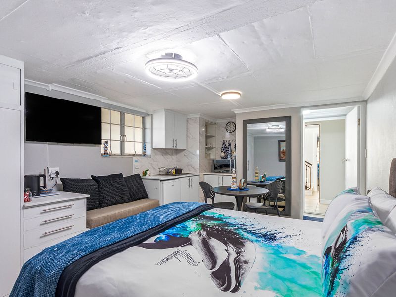 Compact open-plan studio apartment featuring a kitchenette with built-in cabinetry and a functional living and sleeping area.