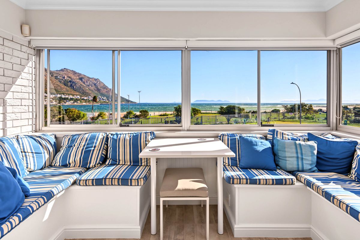 A bright living area featuring built-in bench seating and large panoramic windows offering expansive coastal and mountain views.