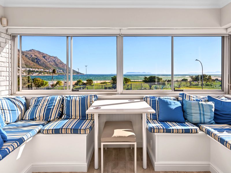 A bright living area featuring built-in bench seating and large panoramic windows offering expansive coastal and mountain views.