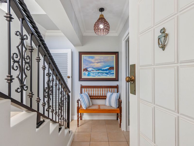 Welcoming entrance foyer featuring a decorative wrought iron staircase railing, tiled flooring, and elegant crown molding details.
