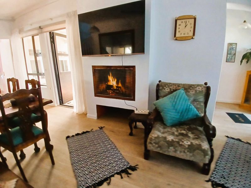 A cozy living room featuring a built-in fireplace, laminate flooring, and direct access to an outdoor area through sliding glass doors.