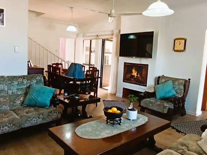 Open-plan living and dining area featuring a built-in fireplace, ceiling fan, and direct access to an outdoor patio through sliding glass doors.