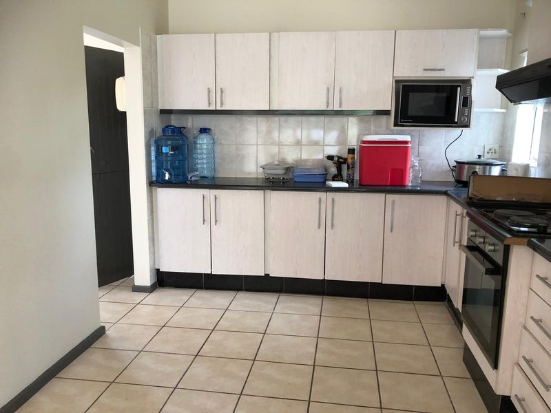 A functional kitchen featuring light-toned cabinetry, dark countertops, tiled backsplash, and integrated appliances including an oven and extractor fan.