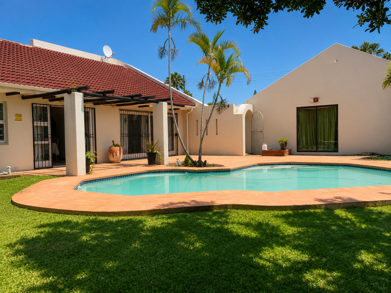 Outdoor pool area featuring a swimming pool with terracotta coping, a covered patio with a timber pergola, and a well-maintained garden.