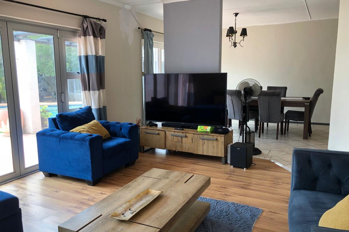 Open-plan living and dining area featuring a mix of laminate and tiled flooring, with direct access to the outdoor patio through aluminium sliding doors.