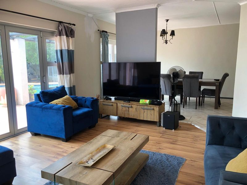 Open-plan living and dining area featuring a mix of laminate and tiled flooring, with direct access to the outdoor patio through aluminium sliding doors.