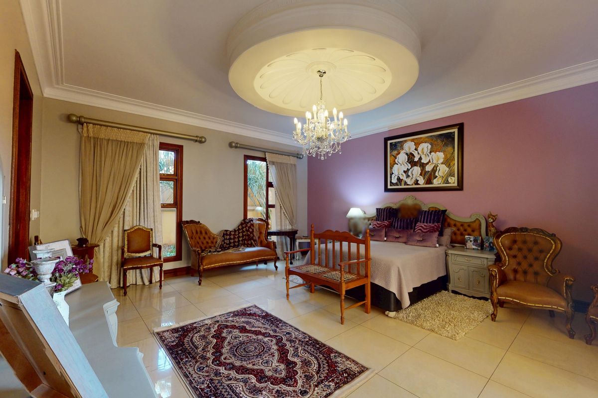 Spacious bedroom featuring a decorative recessed ceiling dome with a crystal chandelier, tiled flooring, and elegant crown molding.