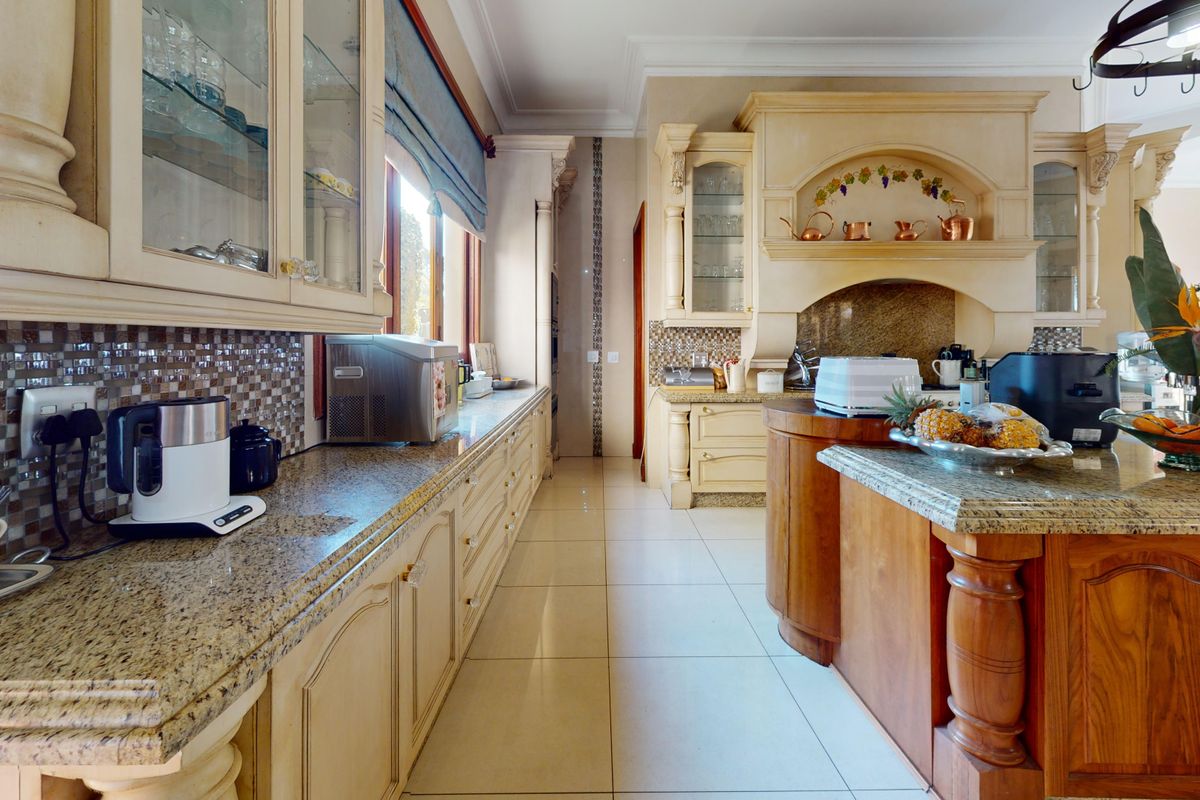 Spacious kitchen featuring custom cabinetry, granite countertops, a central island, and an ornate range hood with decorative tile backsplash.