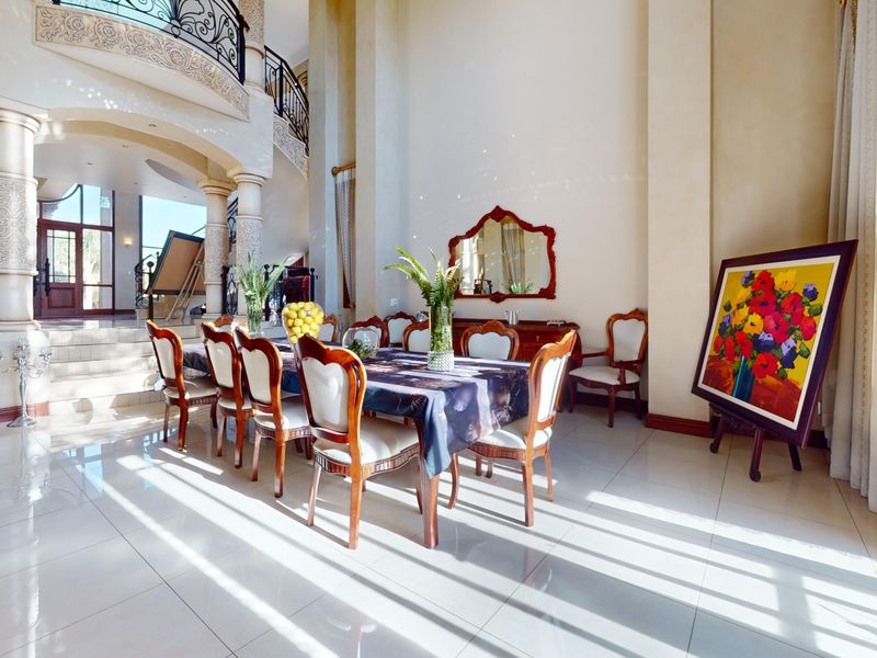 Spacious dining area featuring high double-volume ceilings, elegant arched architectural details, decorative columns, and polished tiled flooring with an open-plan layout.