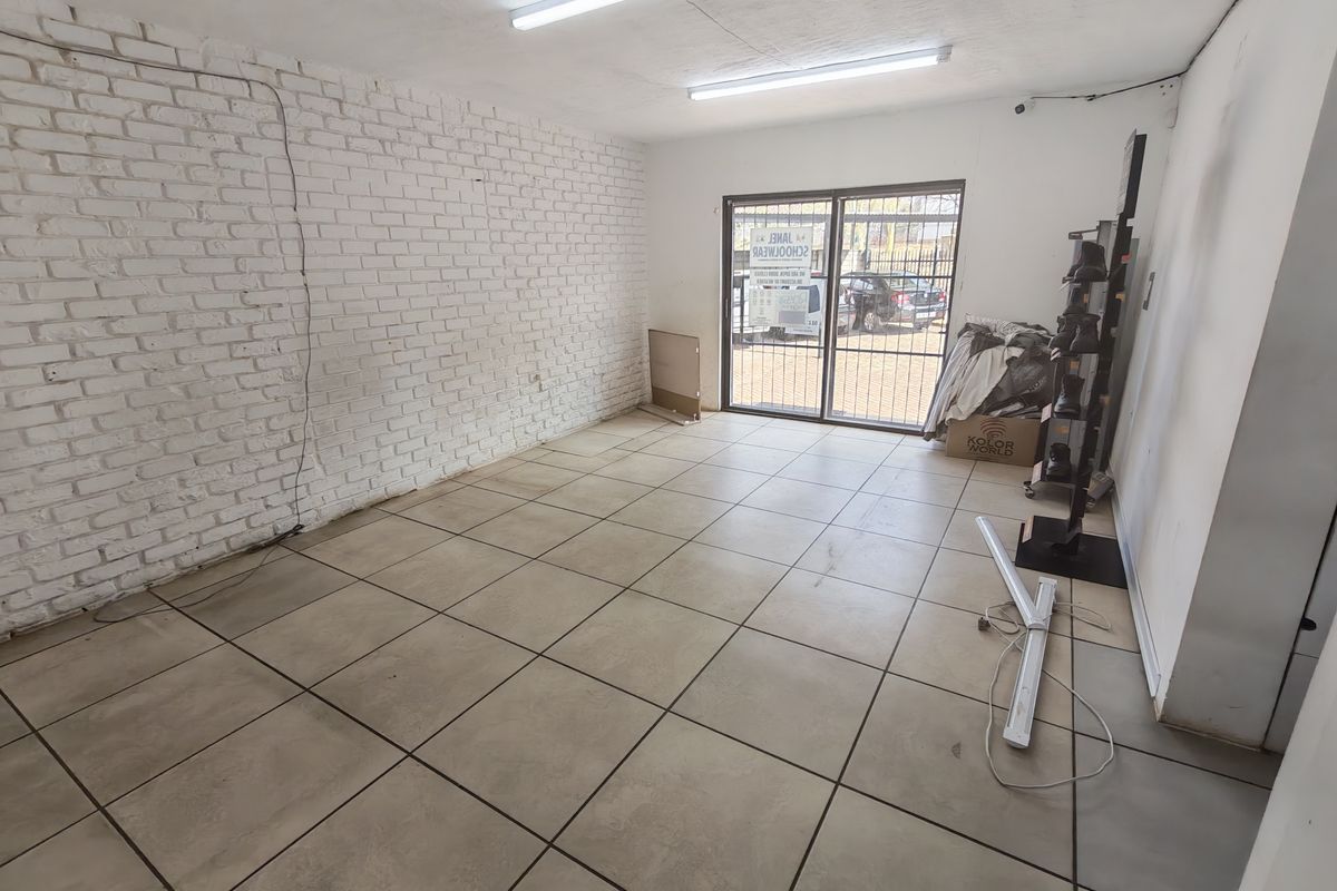 A functional utility space featuring exposed brickwork, tiled flooring, and direct access to the exterior through a secure sliding glass door.