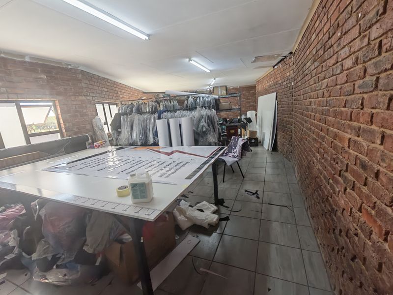 A utility or workshop space featuring exposed brick walls, tiled flooring, and functional overhead lighting, suitable for various commercial or storage applications.
