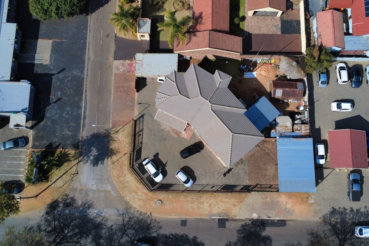 Aerial view of the property showing the roof structure, paved driveway, and surrounding site layout.