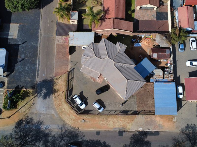 Aerial view of the property showing the roof structure, paved driveway, and surrounding site layout.