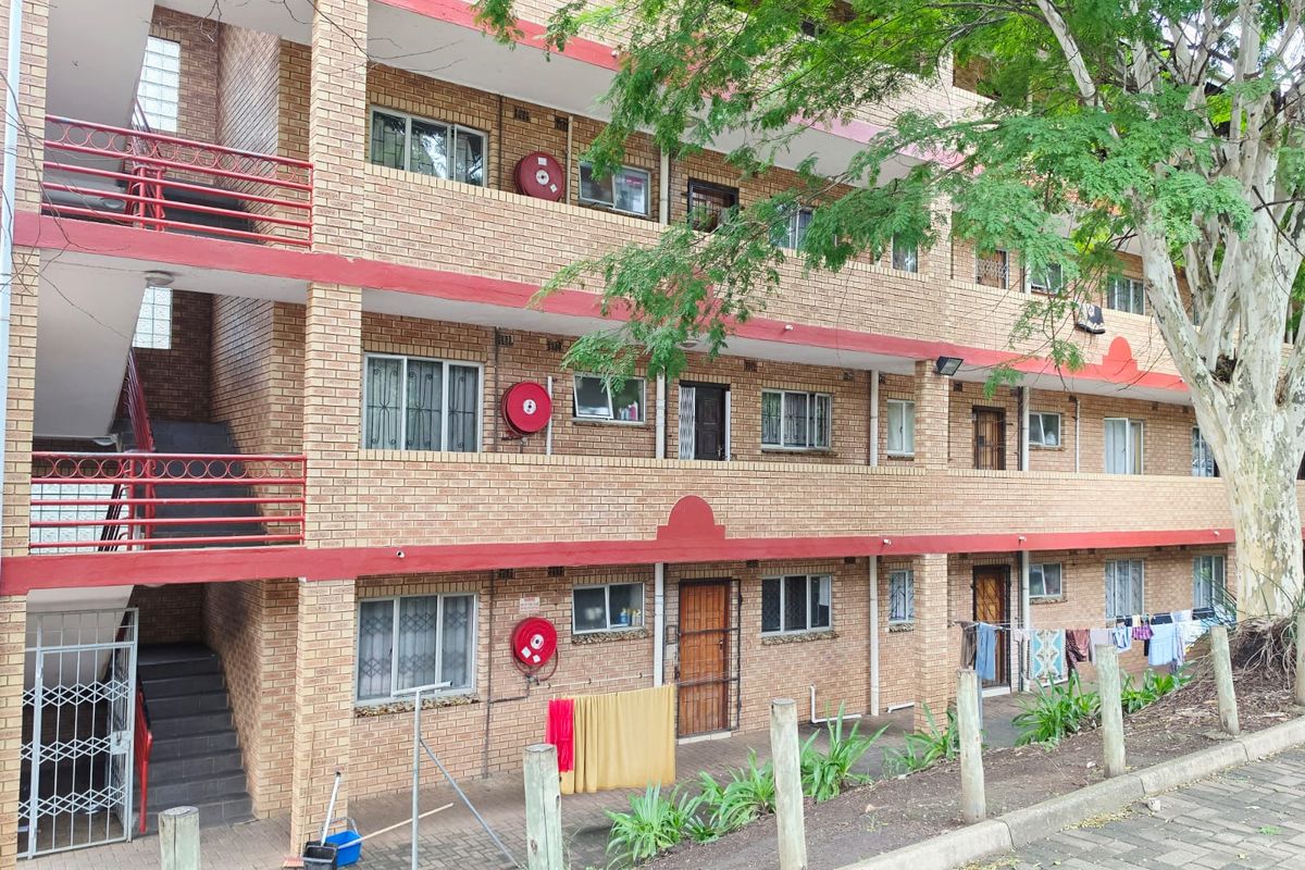 Exterior view of a multi-story apartment complex featuring face brick construction, external stairwells, and integrated fire safety equipment.
