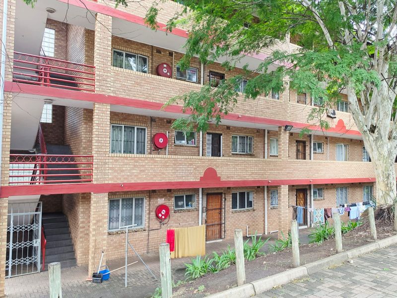 Exterior view of a multi-story apartment complex featuring face brick construction, external stairwells, and integrated fire safety equipment.