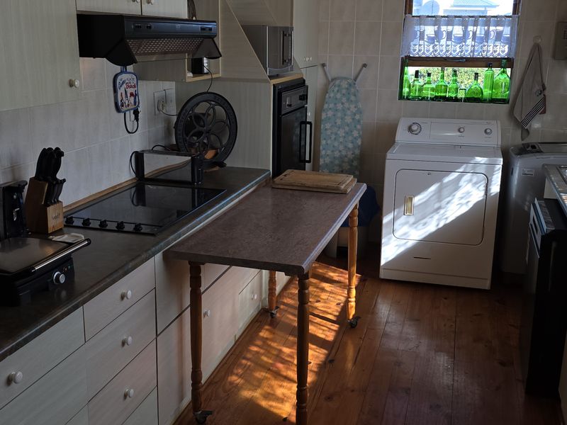 A functional kitchen featuring built-in cabinetry, an electric hob with extractor, built-in oven, and a double stainless steel sink with tiled splashbacks.