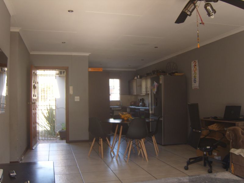 Open-plan living and kitchen area featuring tiled flooring, recessed lighting, and direct access to an exterior entrance with a security gate.