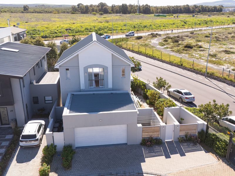 Aerial view of a modern two-story residential property featuring a double garage, paved driveway, and a balcony, situated in a well-maintained estate.
