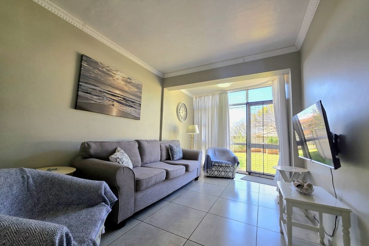 A bright living room featuring tiled flooring, decorative ceiling cornicing, and a sliding glass door providing access to the outdoor area.
