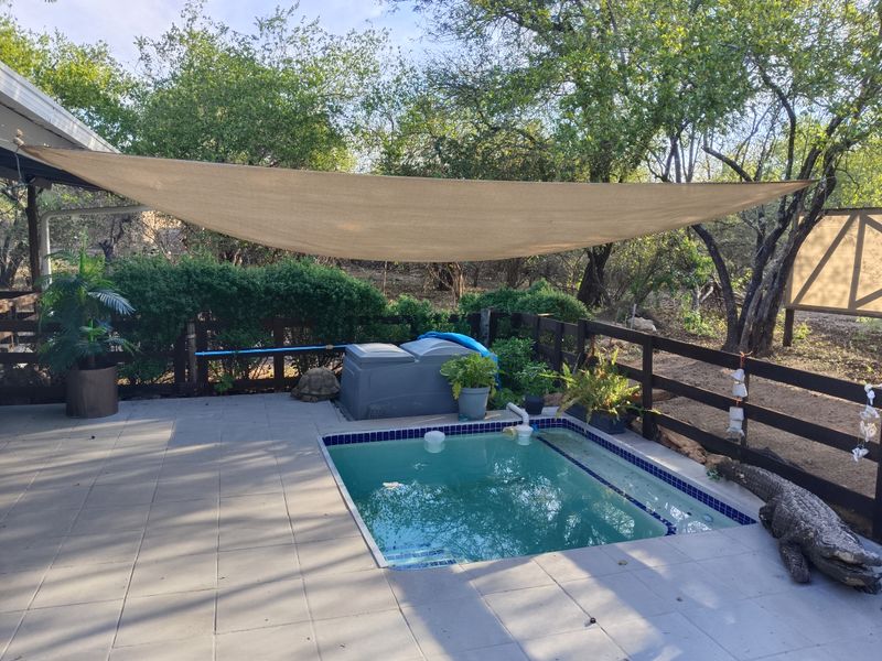 Outdoor pool area featuring a tiled surround, shade sail, and timber fencing, providing a functional space for relaxation and outdoor entertainment.