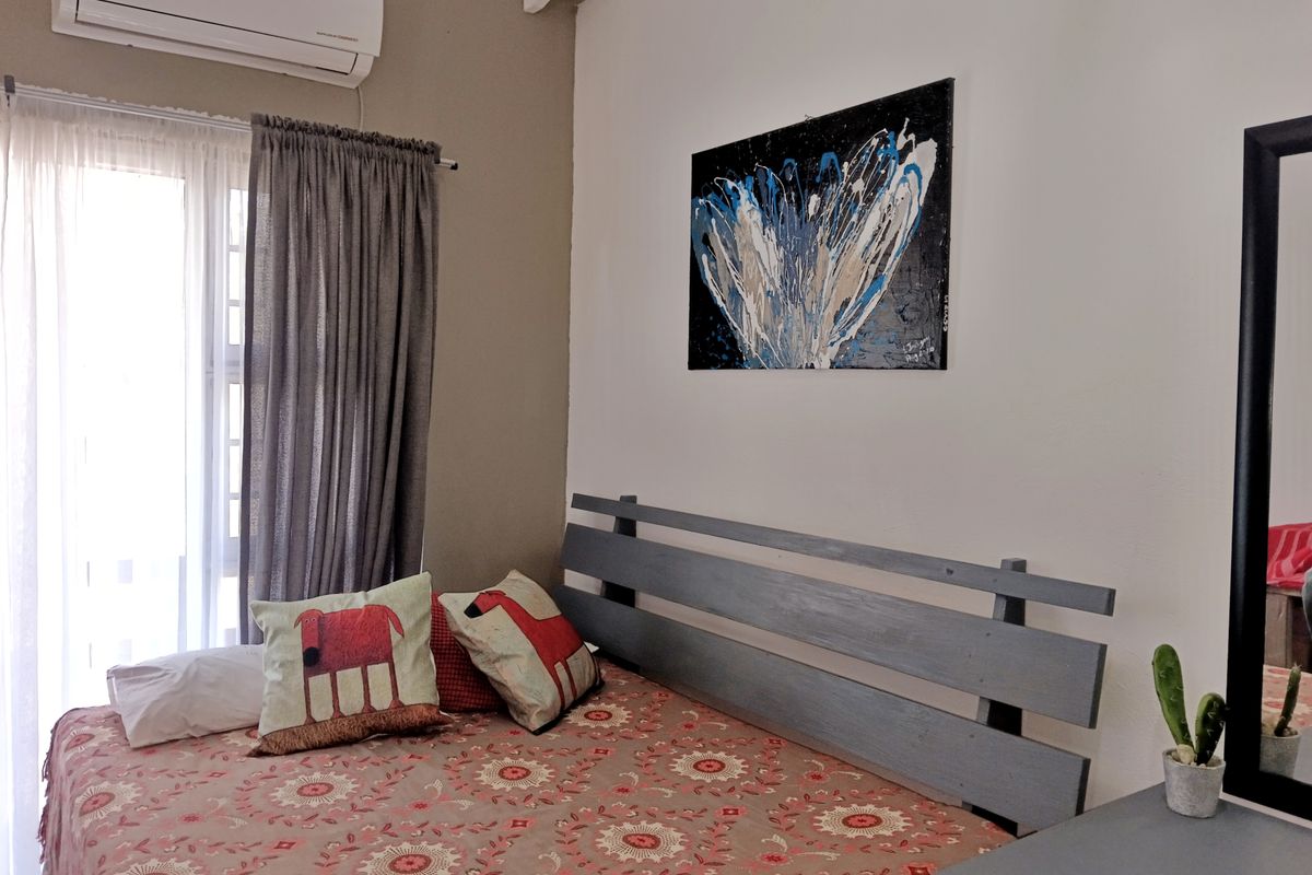 A well-maintained bedroom featuring a wall-mounted split-system air conditioner and a sliding glass door providing natural light.