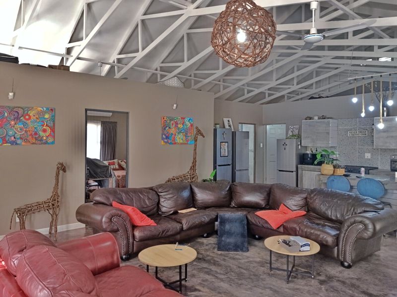 Spacious open-plan living area featuring high exposed roof trusses, concrete flooring, and a functional kitchen with a central island.