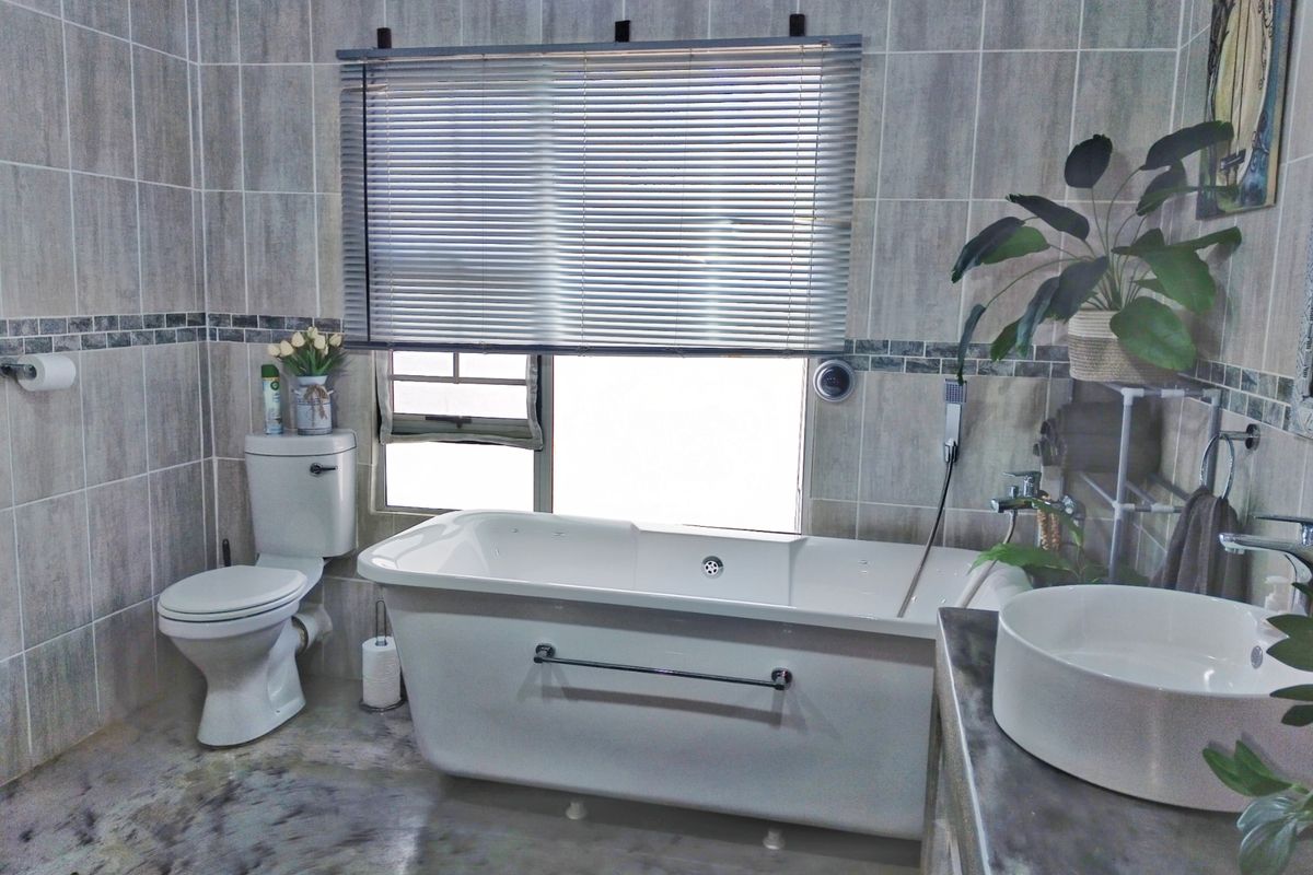 A well-appointed bathroom featuring a freestanding bathtub, modern vessel sink, and neutral wall tiling with a decorative border.