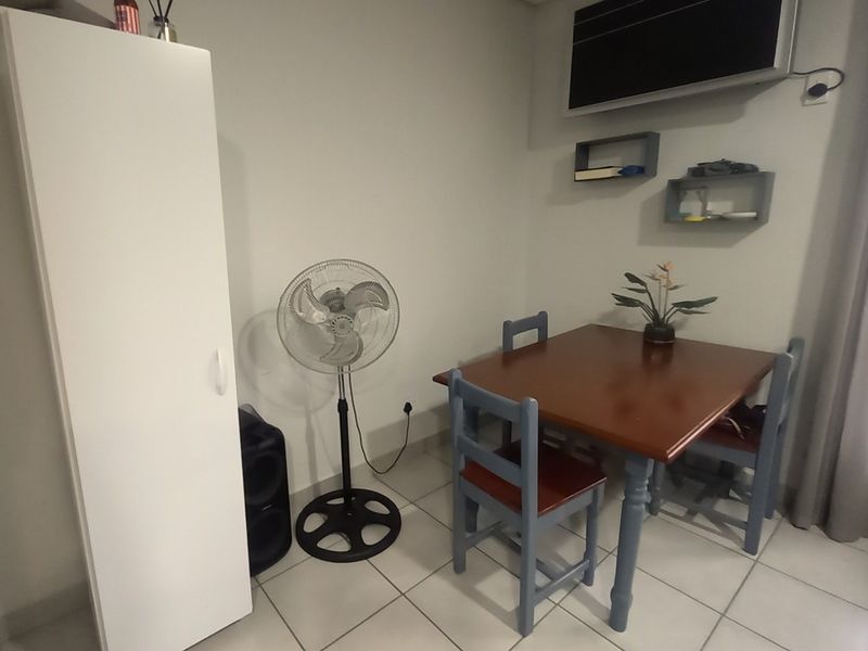 A functional dining area featuring neutral tiled flooring and wall-mounted shelving units, providing a practical space for meals.