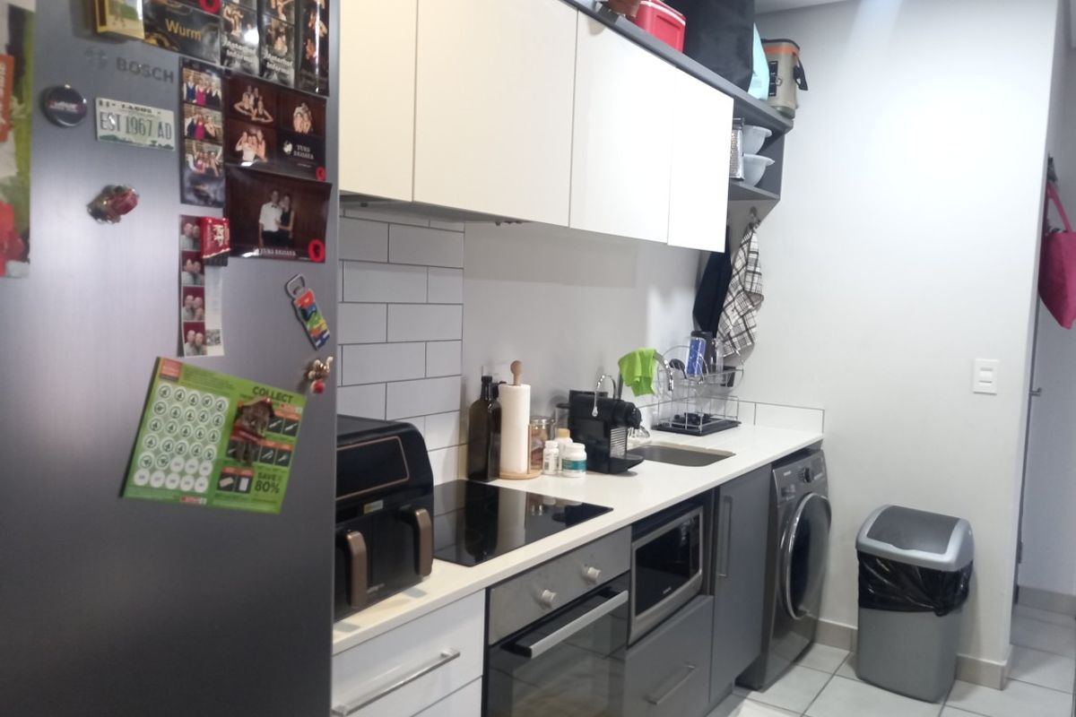 Compact modern kitchen featuring white and grey cabinetry, subway tile backsplash, integrated appliances, and a built-in washing machine.