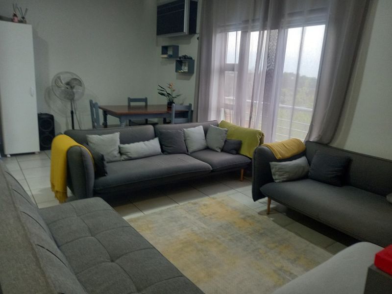 A living room featuring tiled flooring, a wall-mounted air conditioning unit, and a large sliding glass door providing access to the balcony.