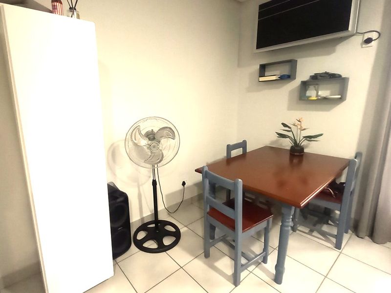 A compact dining area featuring tiled flooring and wall-mounted shelving, providing a functional space for meals.
