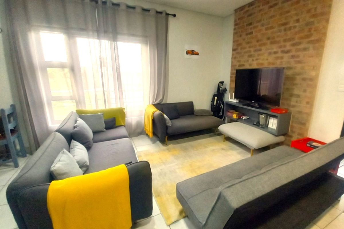 A living room featuring an exposed brick accent wall and tiled flooring, providing a comfortable and functional space.