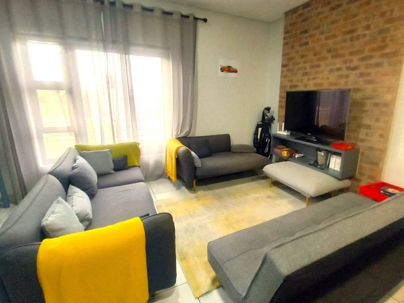 A living room featuring an exposed brick accent wall and tiled flooring, providing a comfortable and functional space.