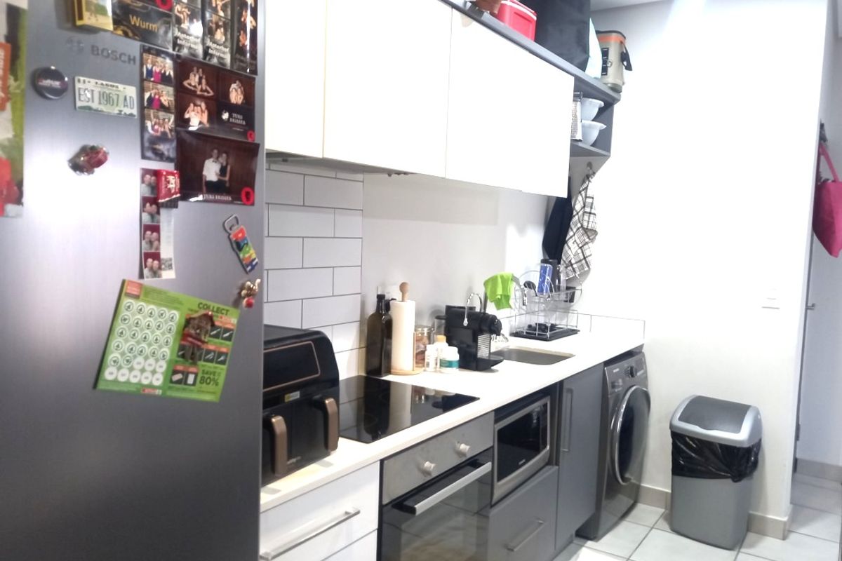 A functional kitchen featuring modern cabinetry, subway tile backsplash, integrated appliances including an oven, hob, microwave, and a built-in washing machine.