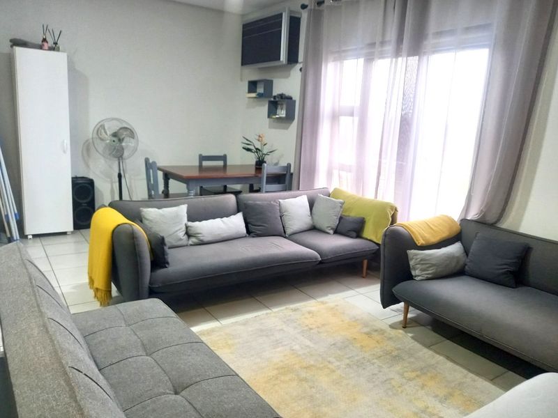 A spacious living room featuring tiled flooring and a large window that allows for natural light, providing a comfortable and functional living area.