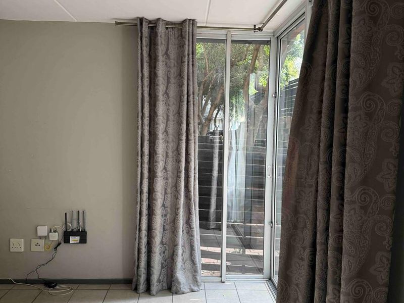 An empty living area featuring tiled flooring and a sliding glass door providing access to an outdoor space.