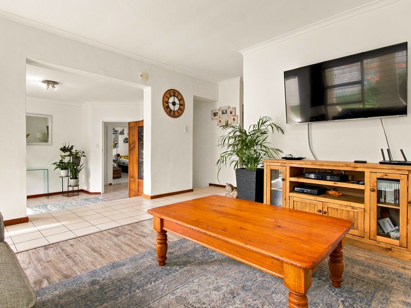 A spacious living area featuring a combination of laminate and tiled flooring with neutral wall finishes and coved cornicing.