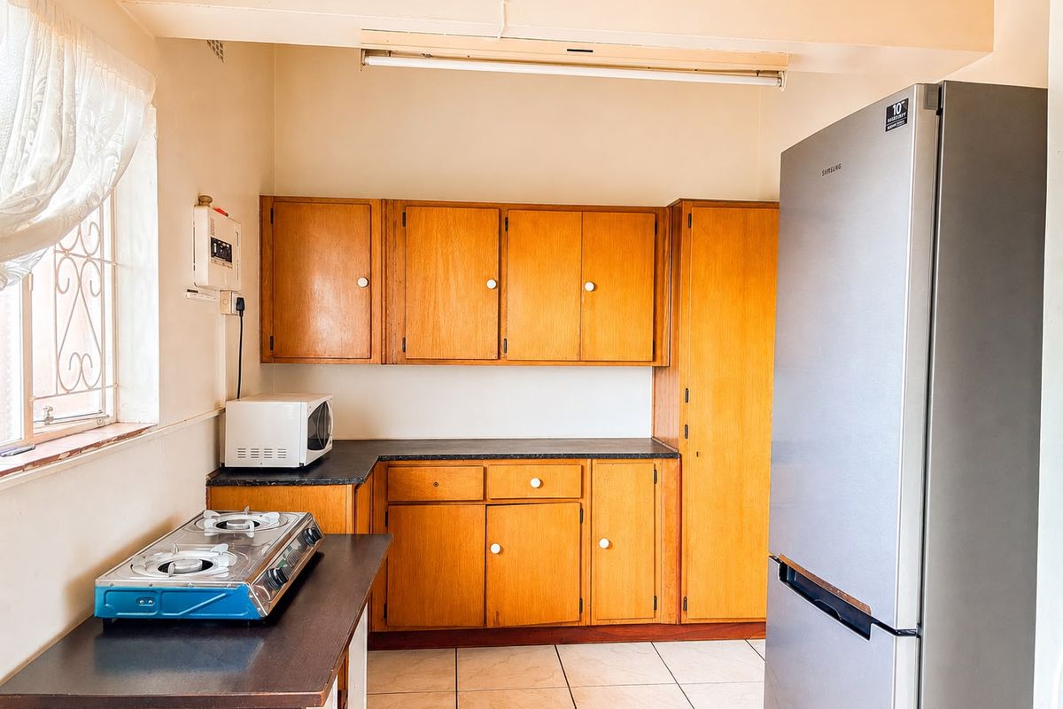 A functional kitchen featuring traditional wooden cabinetry, laminate countertops, and tiled flooring, offering a classic layout with potential for modern updates.