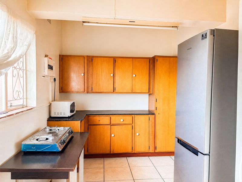 A functional kitchen featuring traditional wooden cabinetry, laminate countertops, and tiled flooring, offering a classic layout with potential for modern updates.