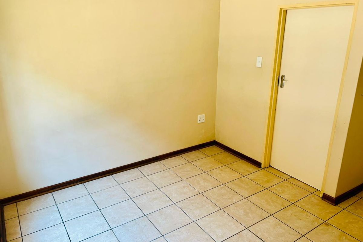 An empty bedroom featuring neutral tiled flooring, painted walls, and a standard internal door, providing a blank canvas for personalization.