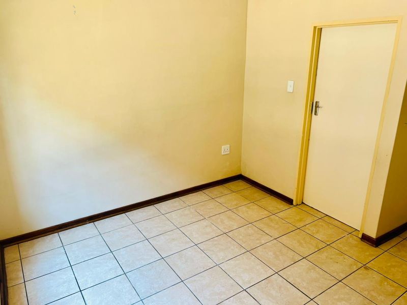 An empty bedroom featuring neutral tiled flooring, painted walls, and a standard internal door, providing a blank canvas for personalization.