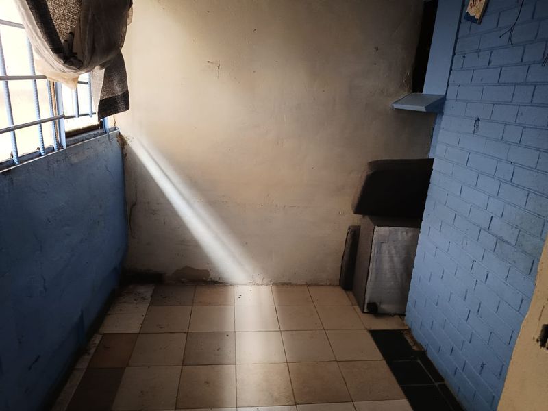 A small, enclosed balcony area featuring tiled flooring and painted brick walls, currently in need of maintenance and cosmetic updates.