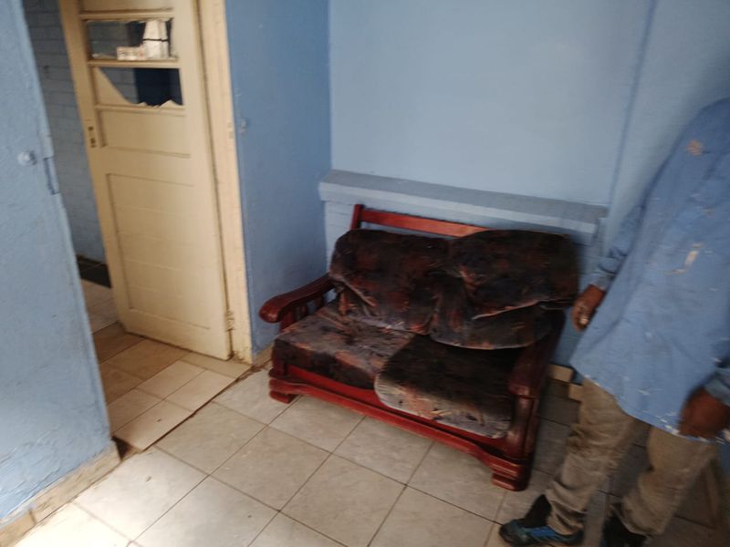 A small living area featuring tiled flooring and a timber door with damaged glass, requiring cosmetic updates and repairs to improve the space.