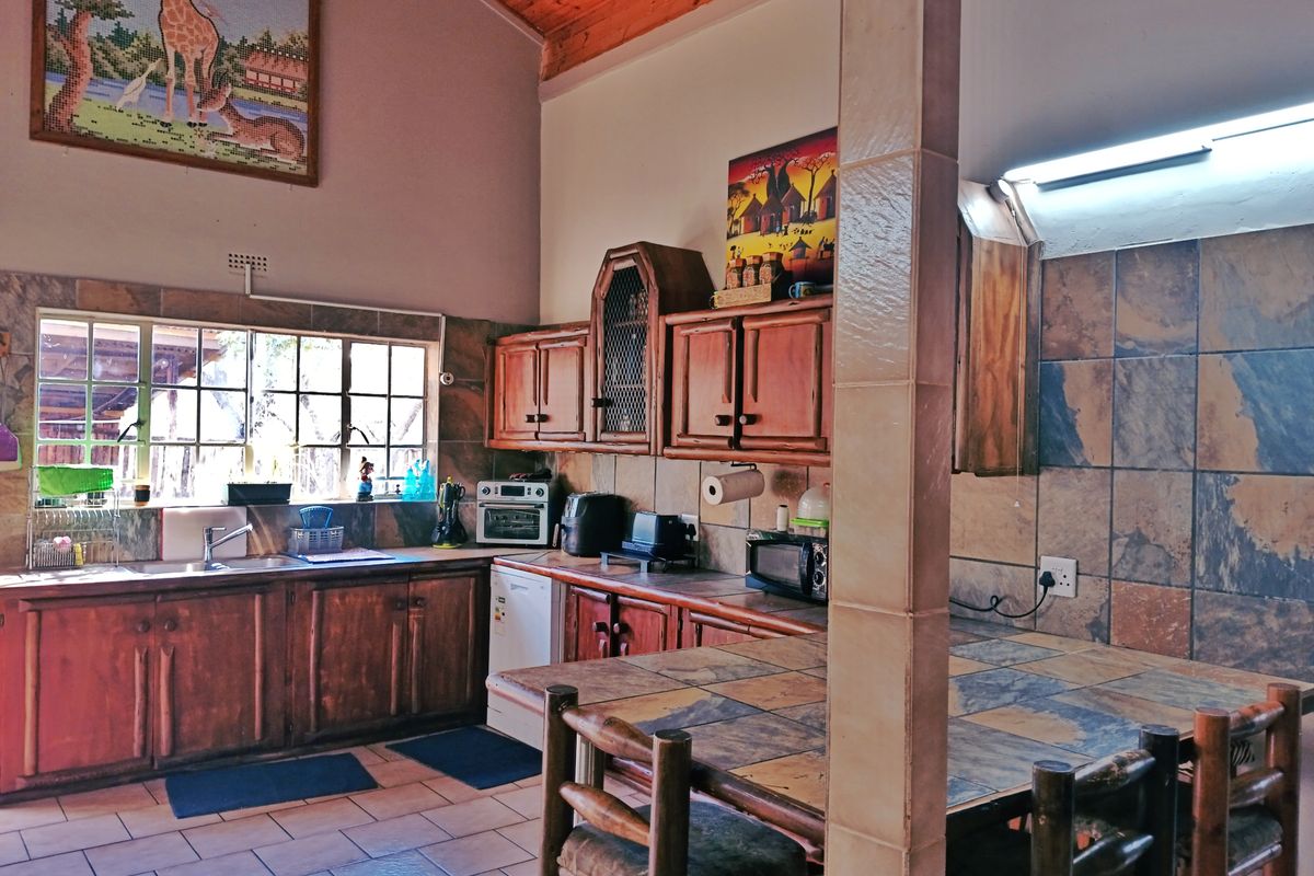 A rustic kitchen featuring wooden cabinetry, tiled countertops, and an exposed timber ceiling, offering a traditional aesthetic with functional workspace.