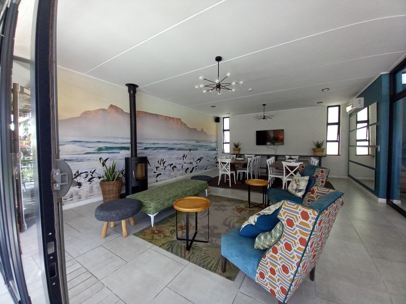 Spacious open-plan living and dining area featuring tiled floors, a modern freestanding fireplace, and large windows providing ample natural light.