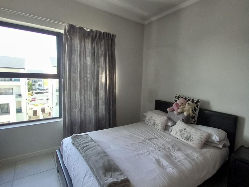 A bedroom featuring tiled flooring, a large window providing natural light, and a central pendant light fixture.